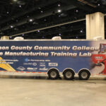 A large trailer on the show floor containing a Davidson County Community College Mobile Manufacturing Training Lab