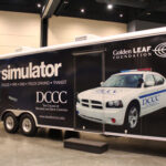 A large trailer on the show floor containing a driving simulator