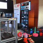 3D printer sits on an information table along with several example objects