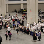 A high-elevation view of the show floor with several dozen participants