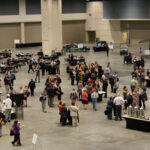 A high-elevation view of the show floor with several dozen participants