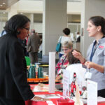 A participant gets information from a representative at an information table