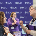 Two people have a discussion in front of an ECU information desk