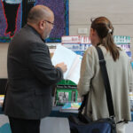A participant gets information from a representative at an information table